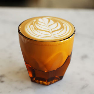 notNeutral VERO Cappuccino Glass 6oz in amber glass with latte art on marble surface