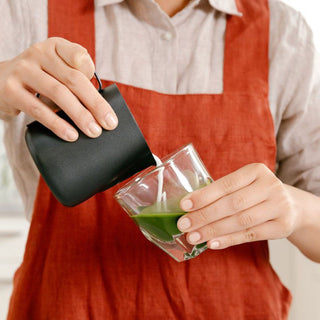 notNeutral VERO Cappuccino Glass 6oz held at angle while pouring milk into green matcha tea beverage