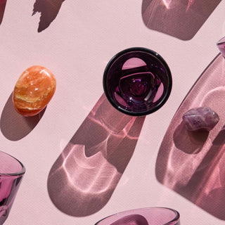 notNeutral VERO Espresso Glass 3oz in purple glass casting intricate shadows on pink surface with stones nearby