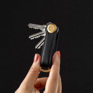 Orbitkey Saffiano Leather Key Organiser in black held between fingers with keys fanned out