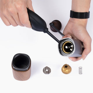 Timemore Air Blower with matte black silicone used to clean silver coffee grinder parts on white surface