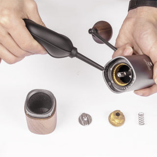 Timemore Air Blower in black silicone cleaning residue from a disassembled manual coffee grinder