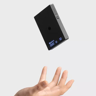 Timemore Black Mirror Mini Coffee Scale showing digital display with hand beneath and black reflective surface