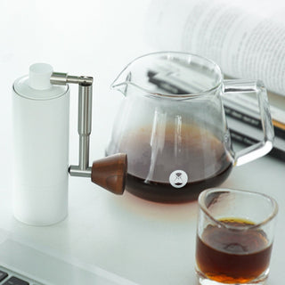 Timemore Chestnut Nano 3 Grinder with aluminum body and walnut handle next to glass coffee server and cup