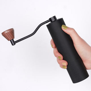 Timemore Chestnut Slim 3 Grinder held showing black textured aluminum body and wooden handle knob