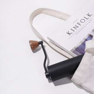 Timemore Chestnut Slim 3 Grinder with textured black body and wooden handle on white fabric bag background