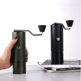 Timemore Chestnut X Lite hand grinder in green held and matte black model on stacked books against white background
