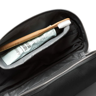 Bellroy Toiletry Kit Plus open showing black interior with toothbrush and toothpaste inside compartment