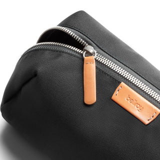 Bellroy Toiletry Kit Plus in black recycled fabric with leather zipper pull and logo patch close-up