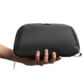 Bellroy Toiletry Kit Plus in black recycled fabric held by hand showing compact design