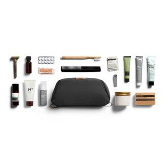 Bellroy Toiletry Kit Plus with black recycled fabric and assorted grooming essentials organized around it